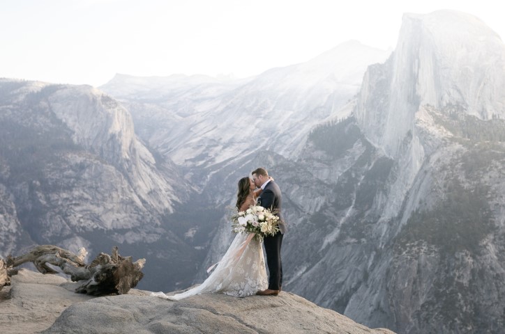 Bride and groom kiss in mountains