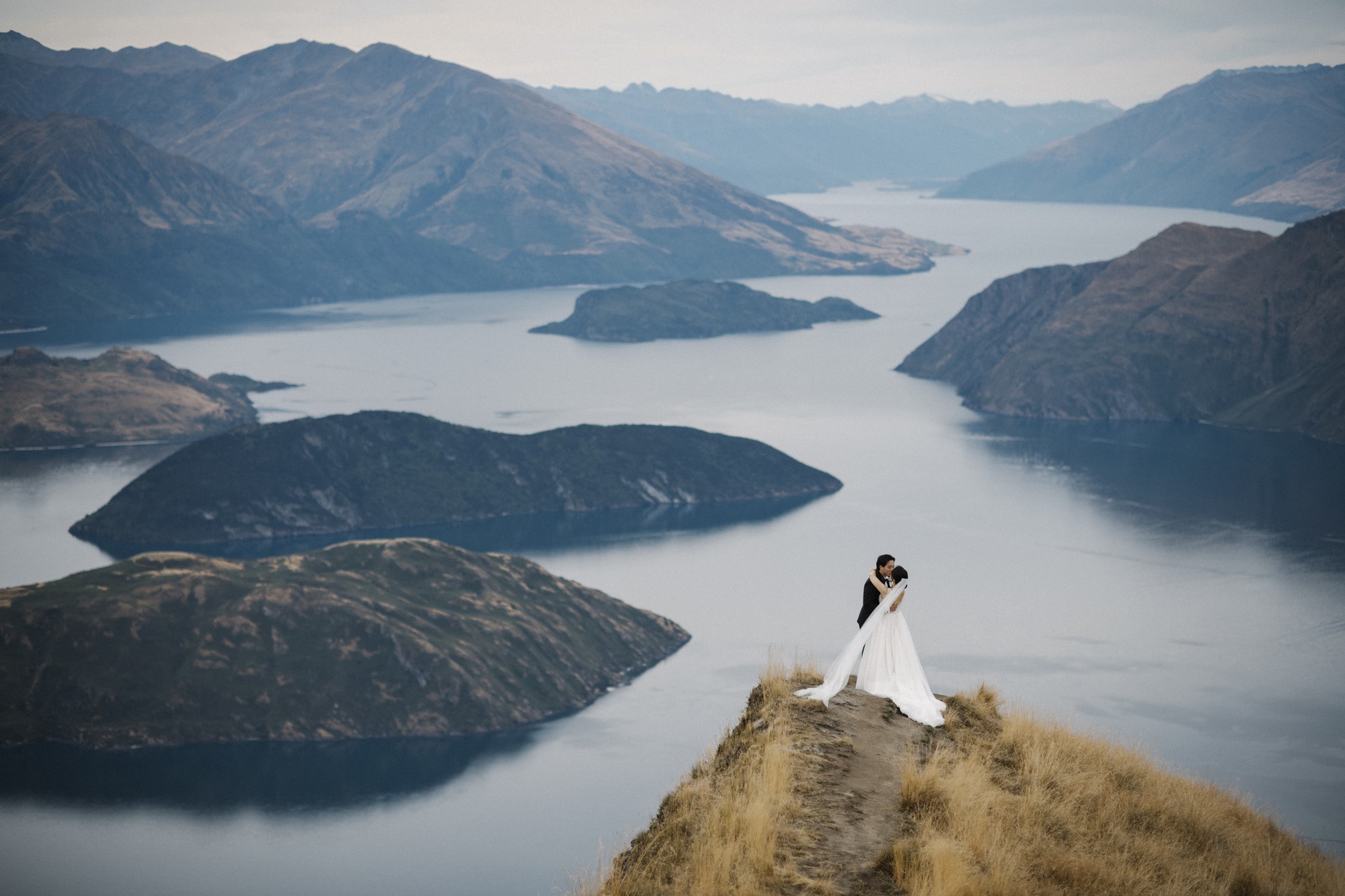 Bride and groom kiss on cliff