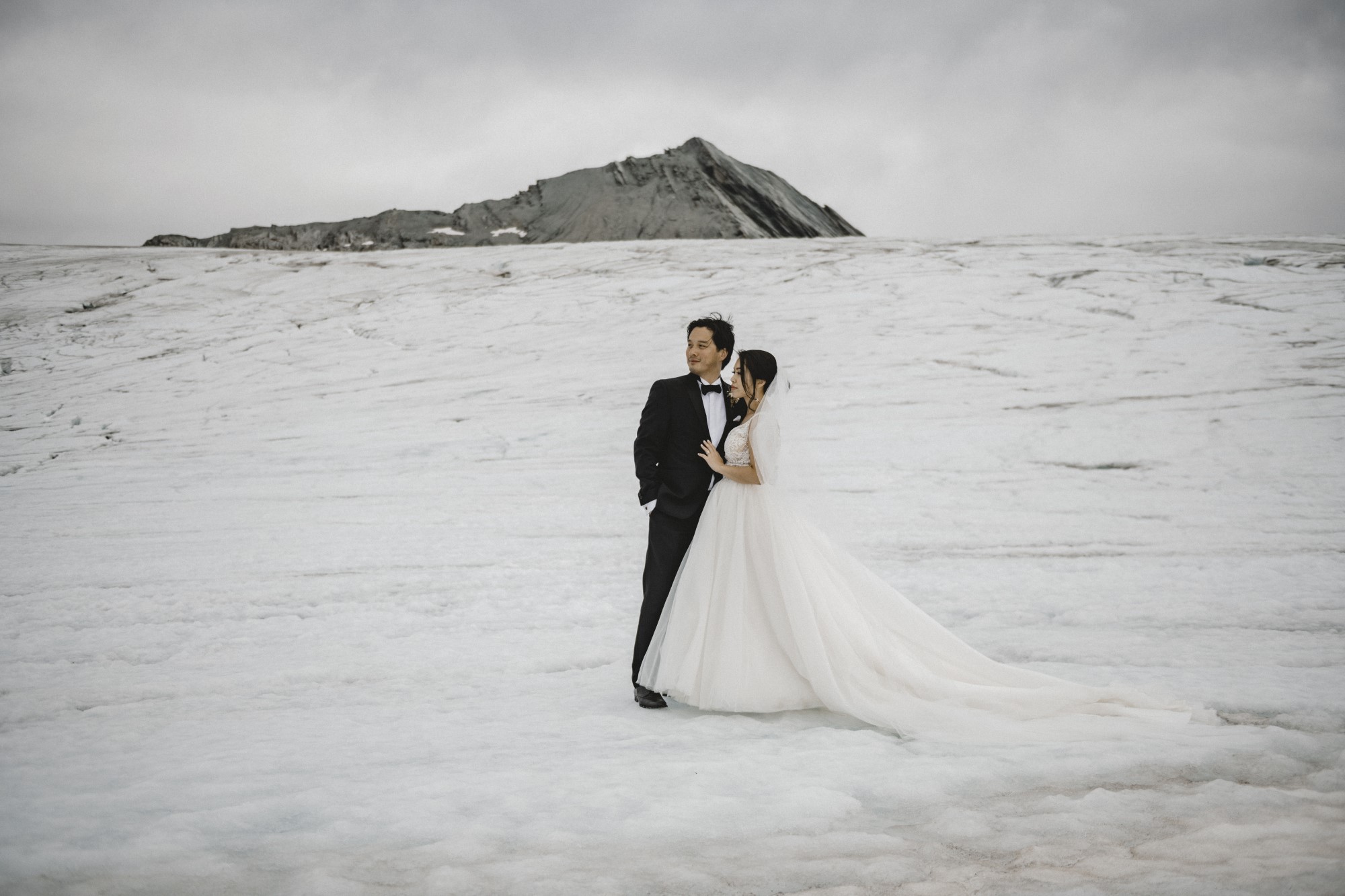 Brautpaar posiert in Schneelandschaft.