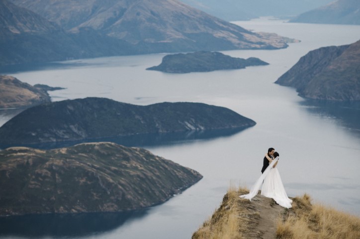 Hochzeitspaar posiert in Berglandschaft.