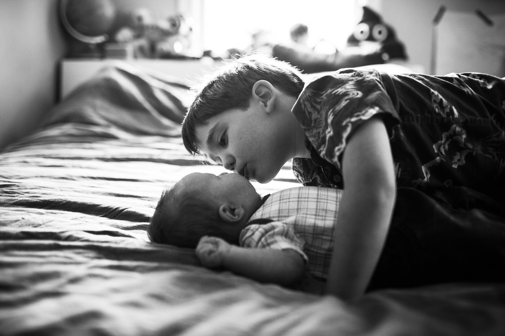 Young boy kisses baby sibling
