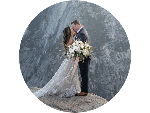 Newlywed couple kissing with a mountainous backdrop