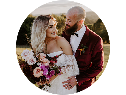 Bride holding colorful bouquet with groom as they pose for wedding portrait