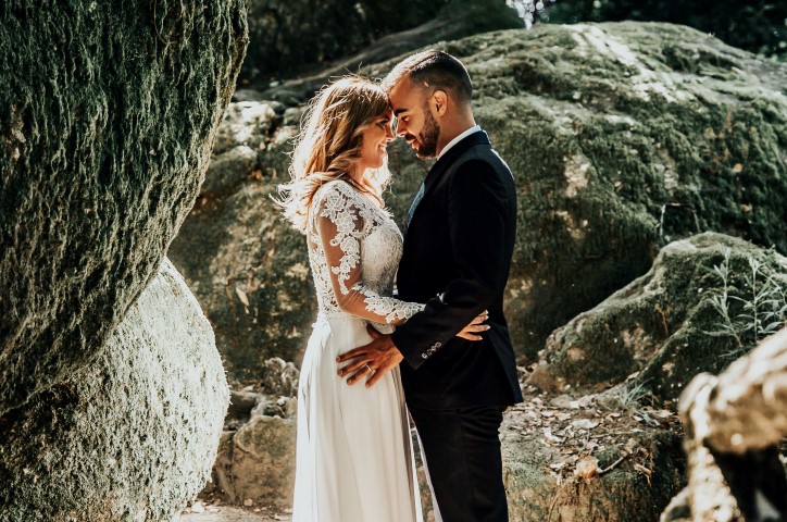 Couple de jeunes mariés posant dans un paysage naturel.