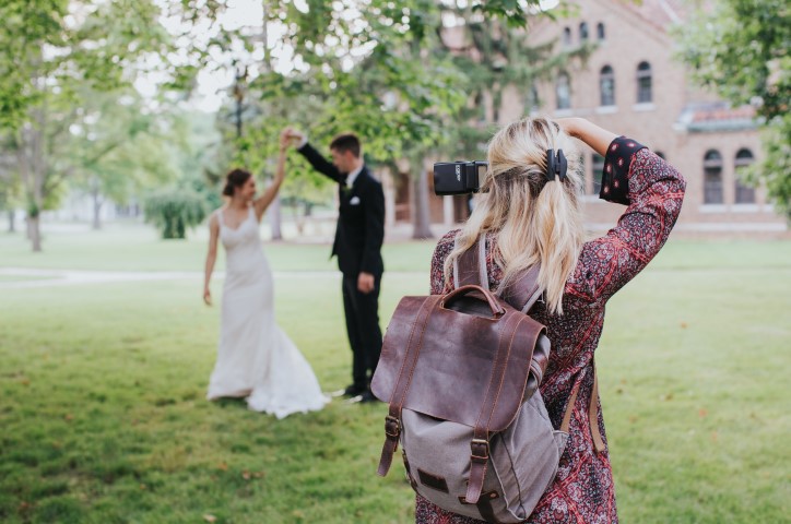 Hochzeitsfotografin schießt Foto von Brautpaar in Garten.