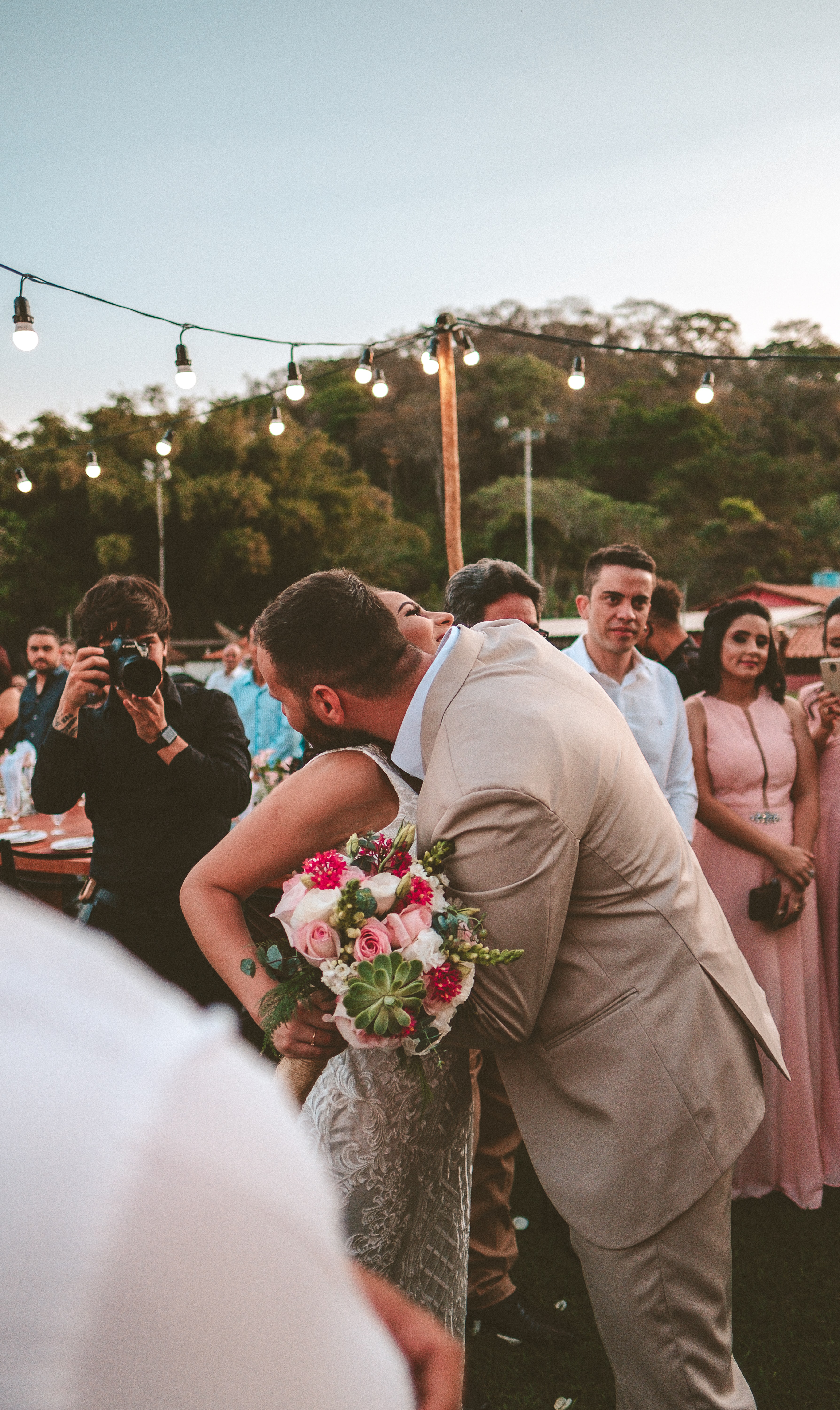 Couple s'embrassant avec un photographe de mariage en arrière-plan.