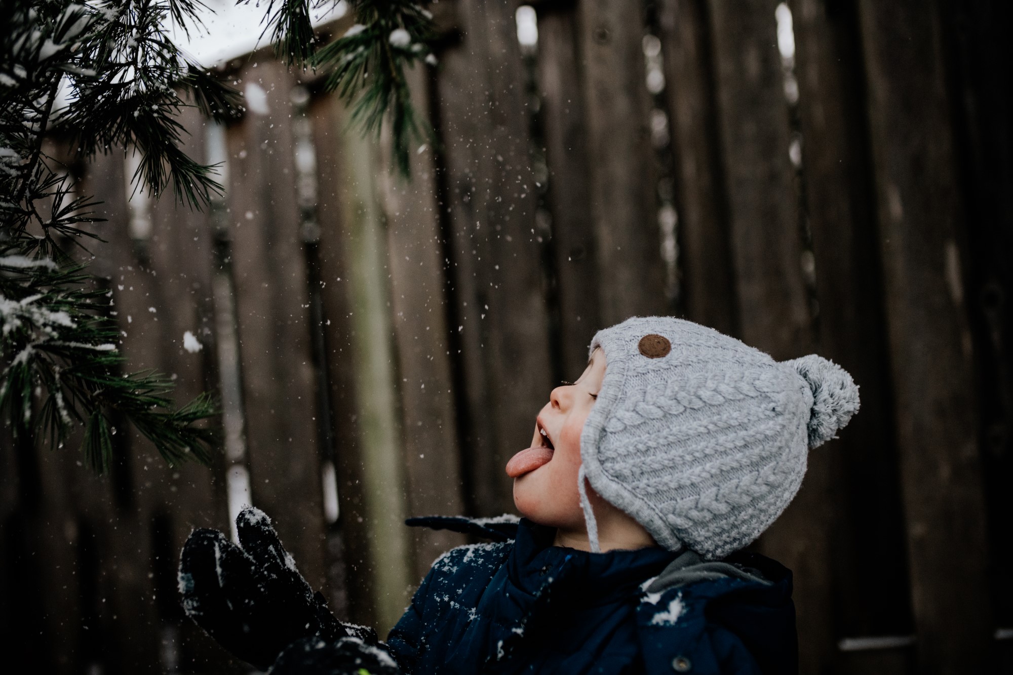 Young child in beanie catching snow