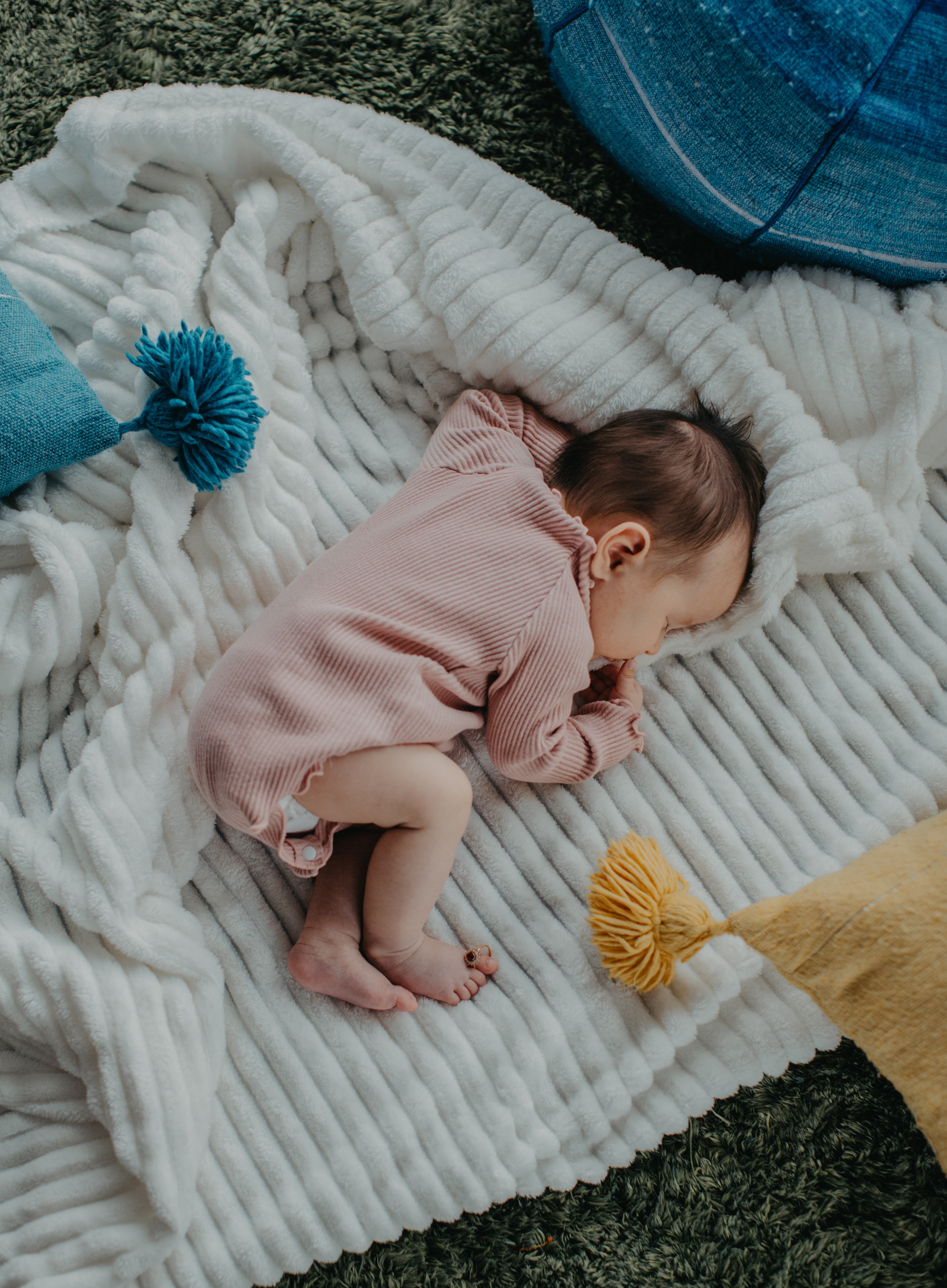 Baby schläft auf einer Decke zwischen Kissen.