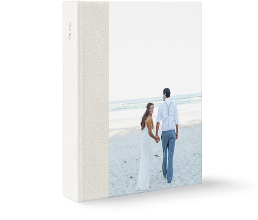 Um grande álbum de fotos de casamento em couro com um casal recém-casado na praia, na capa.