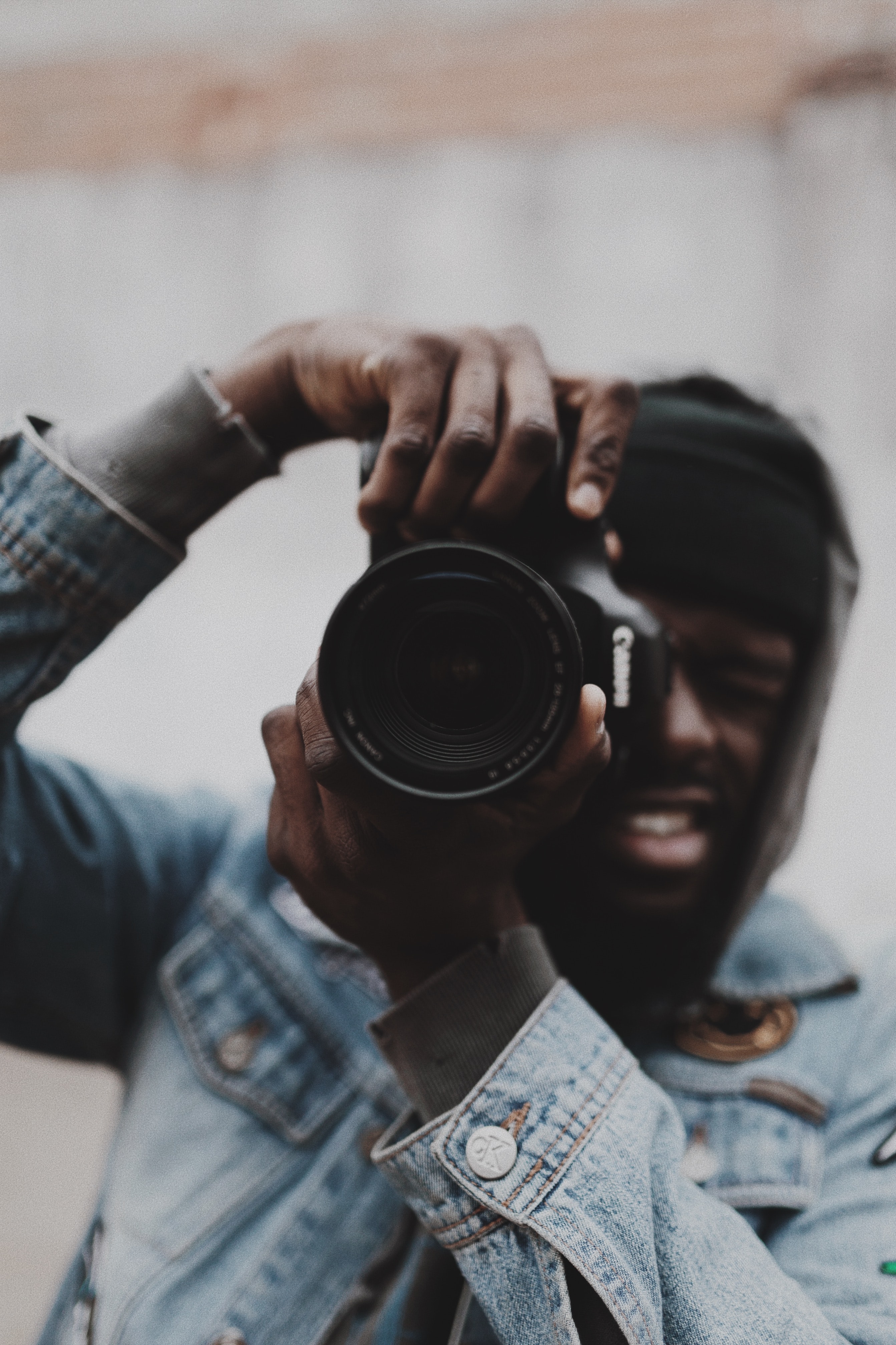 Un homme portant une veste en jean prend une photo avec un appareil photo reflex.