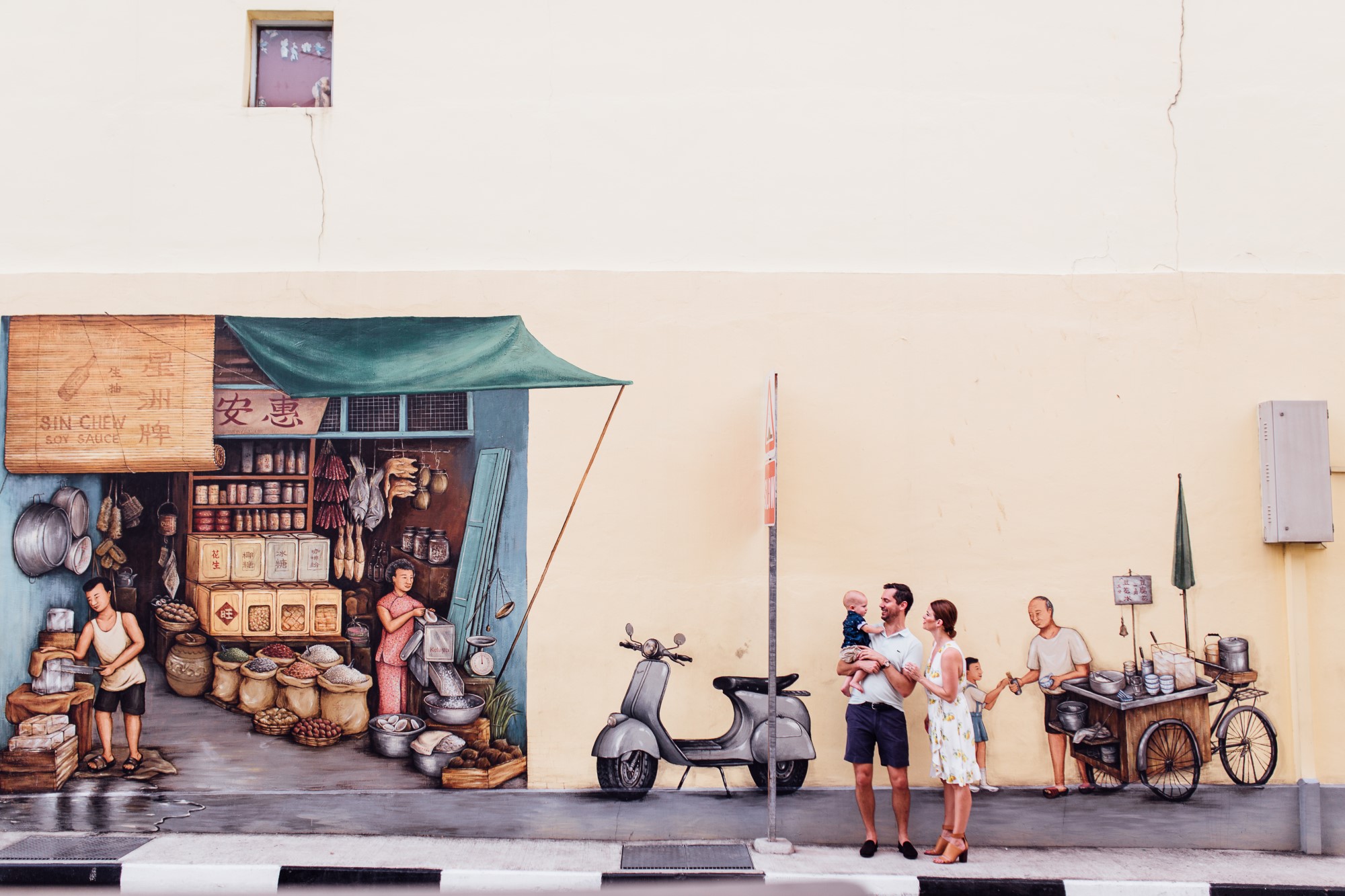 Young family posing against Provision Shop mural in Singapore