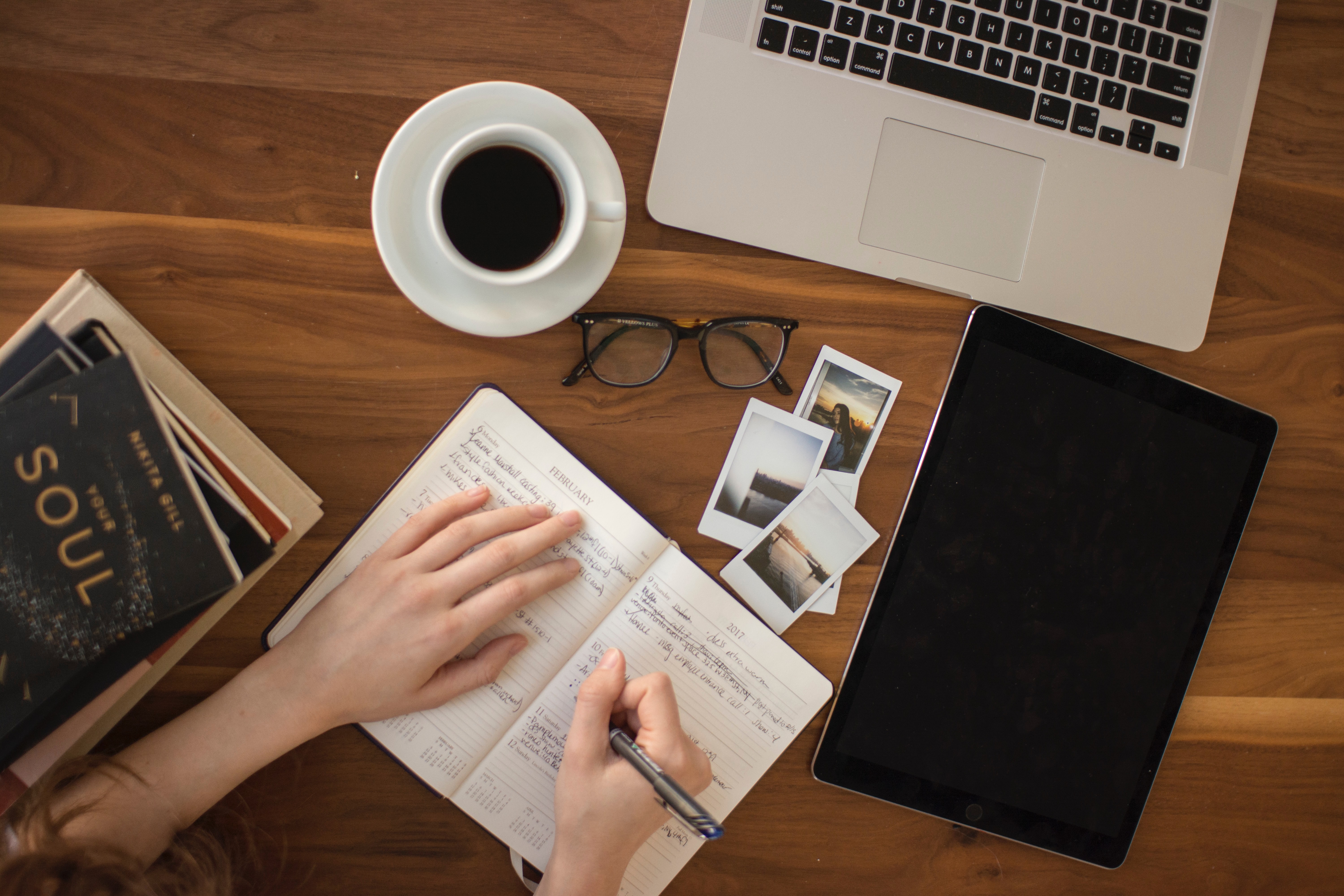Un carnet de notes à côté des photos, de l'ordinateur portable et du café.