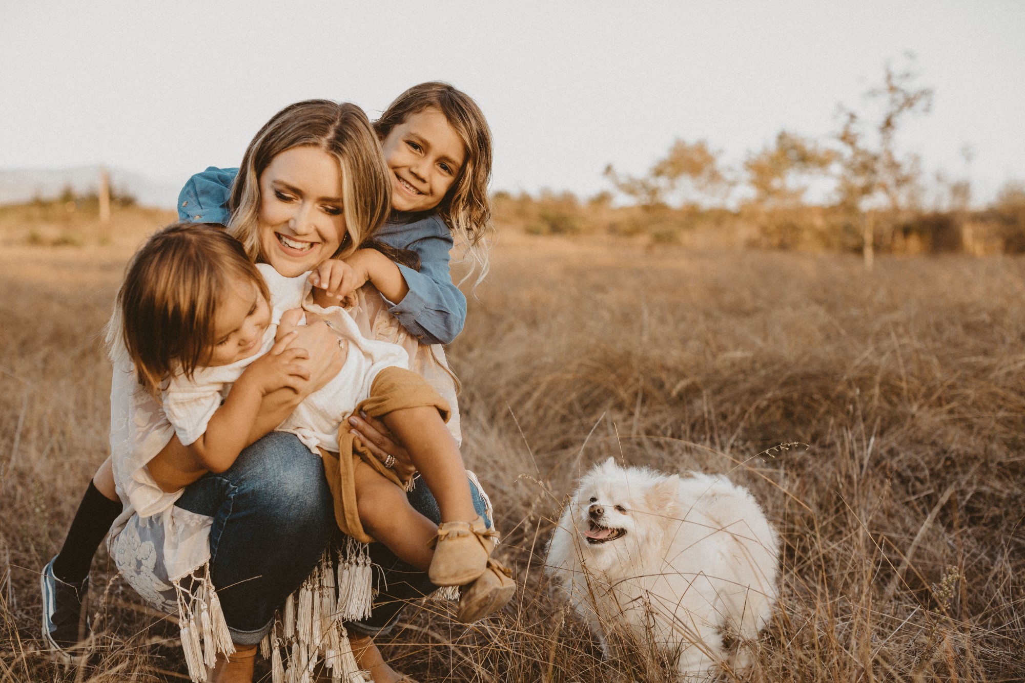 Woman with dog cuddling two children