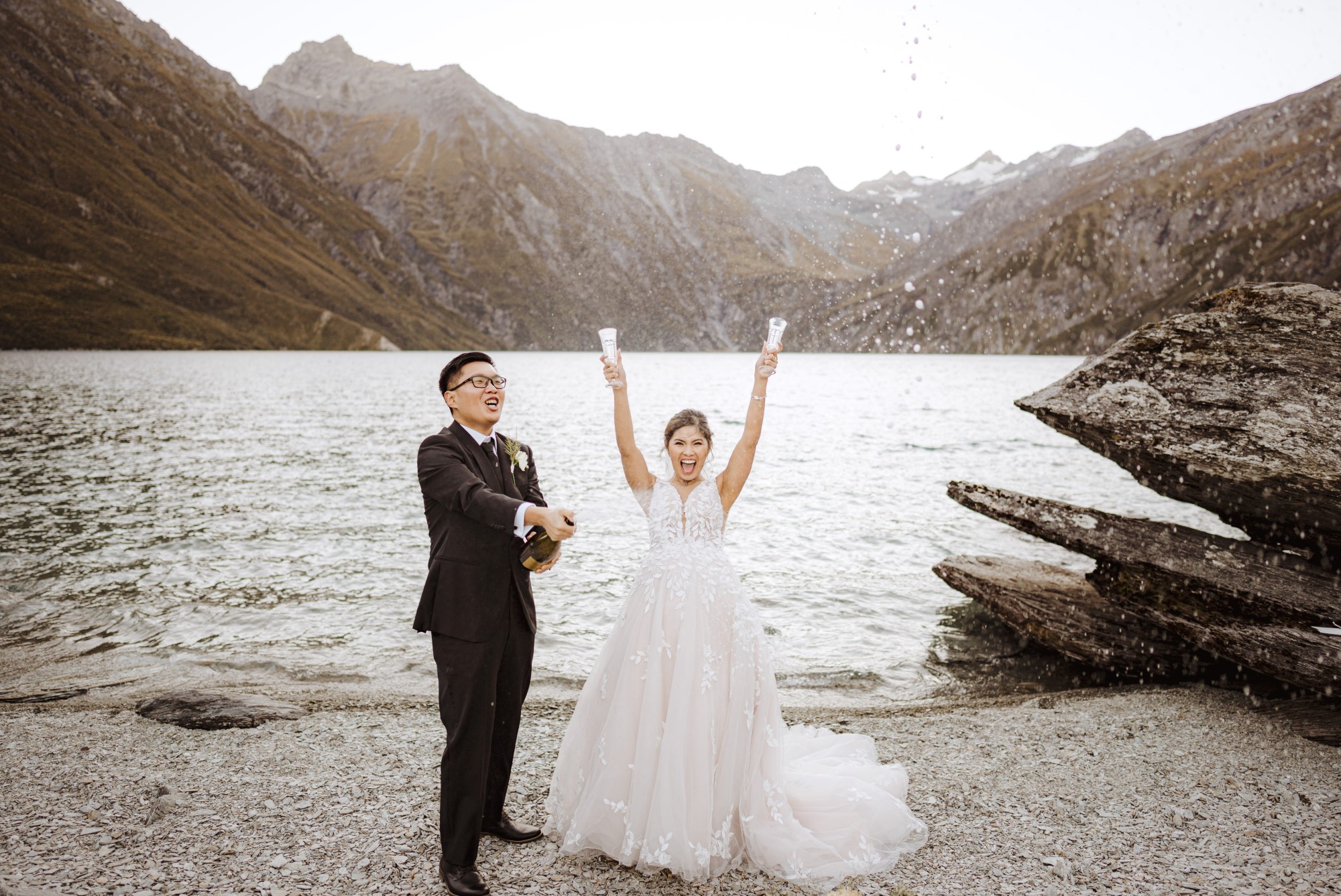 Newlyweds toasting champagne on the shore
