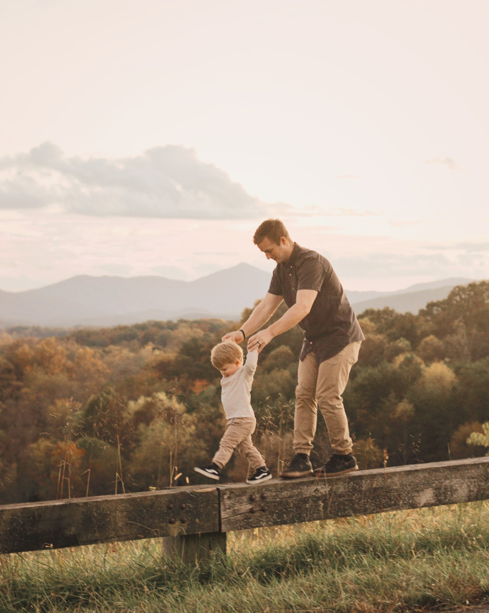 Man and child balance on low fence