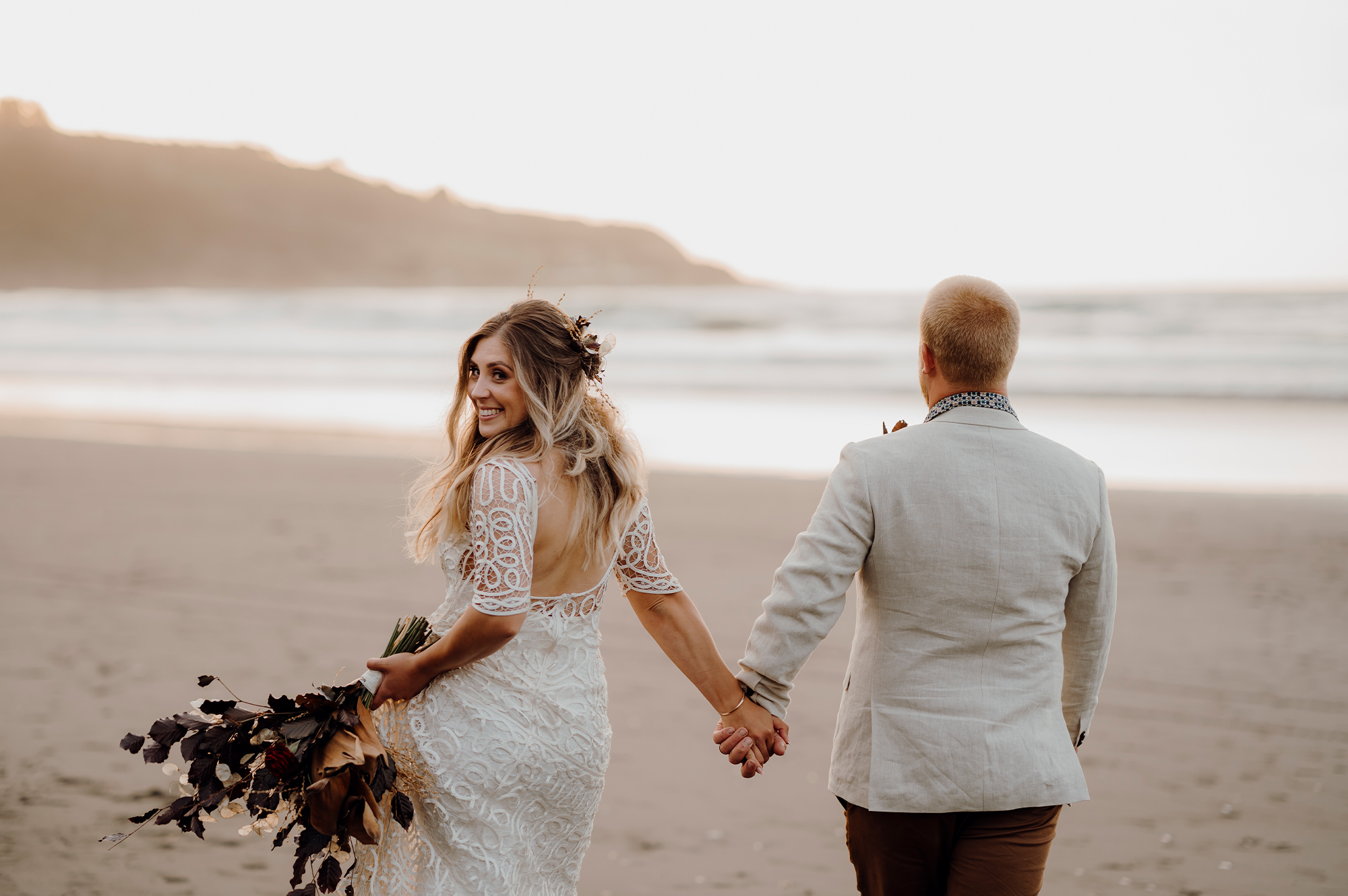 Newlyweds holding hands on beach