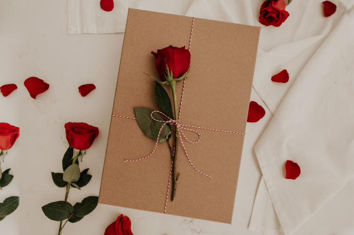 Paquet cadeau avec des roses sur lit.
