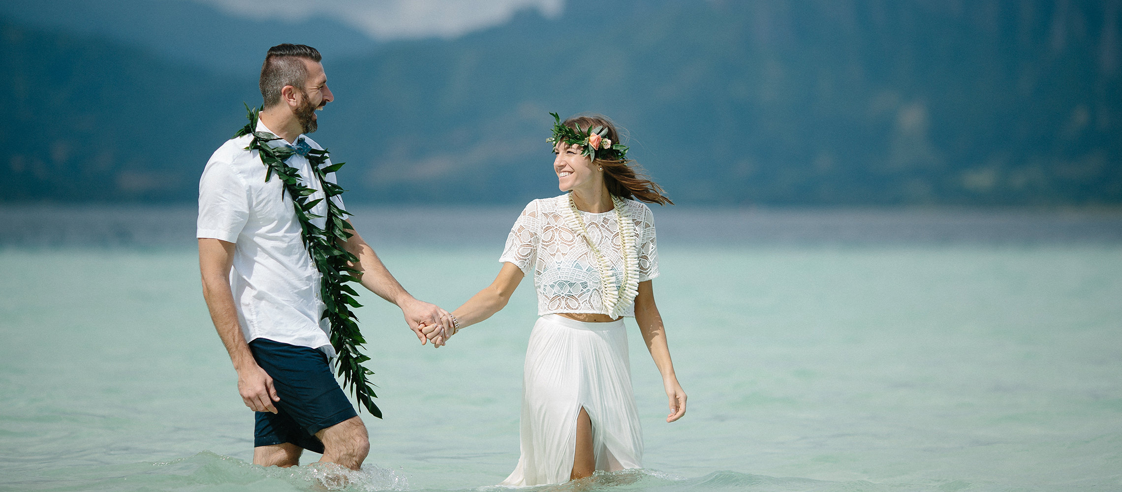 Couple standing in water on their wedding day.