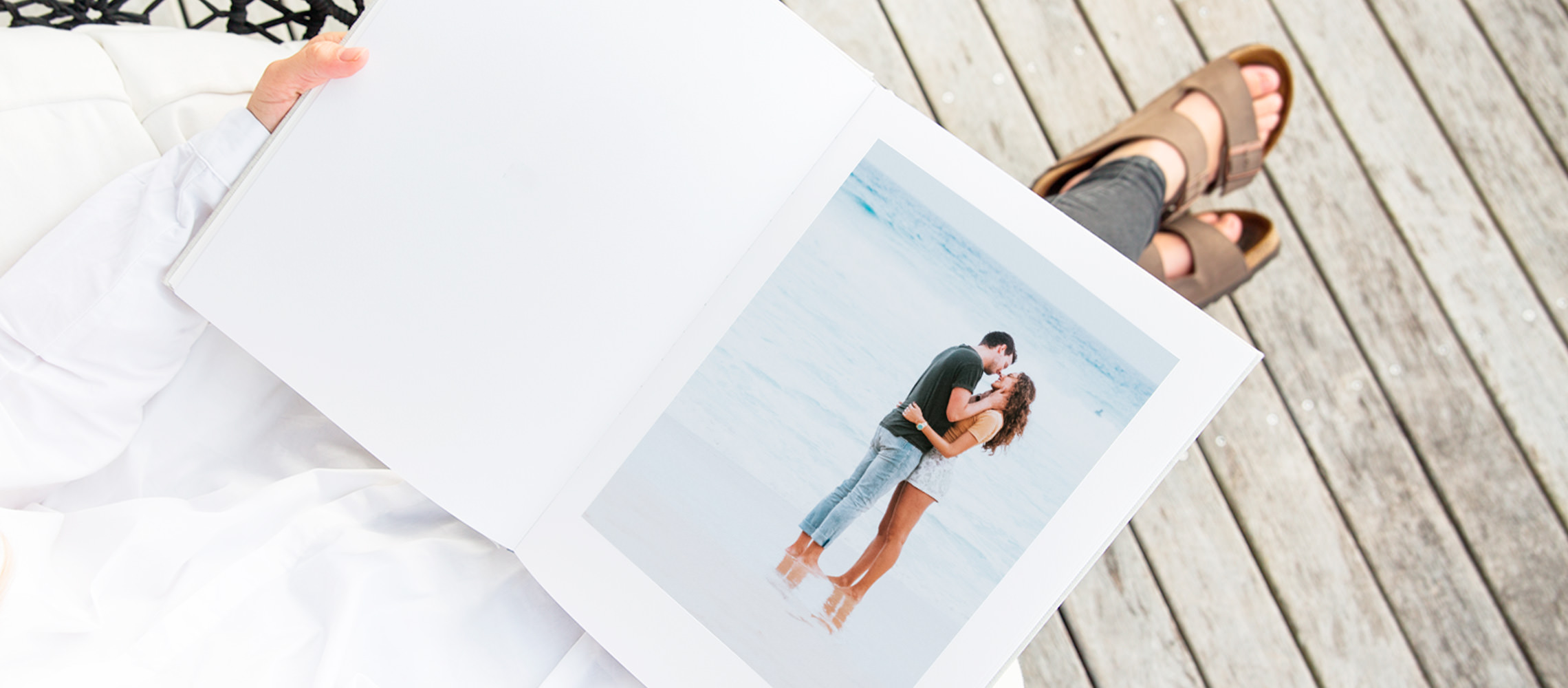 Aufgeschlagenes Fotoalbum mit Bild eines Paares, das sich am Strand küsst.