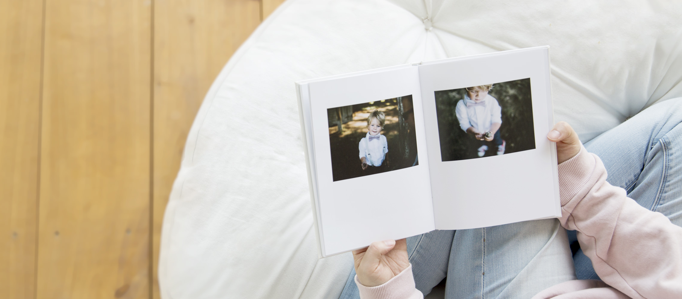 Person on a bean bag flipping through a photo book with images of a young boy.