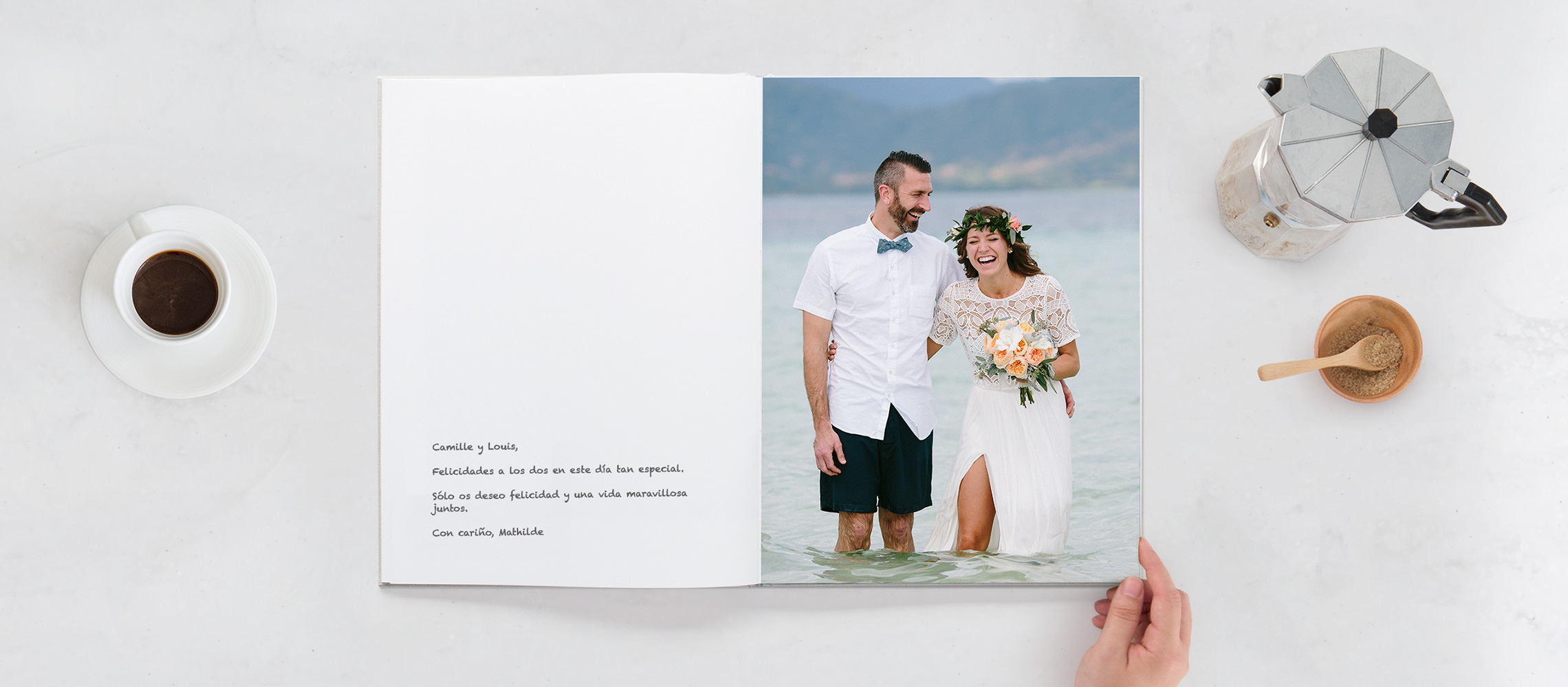 Libro de invitados abierto con los novios riendo en el agua y escribiendo en la página en blanco.