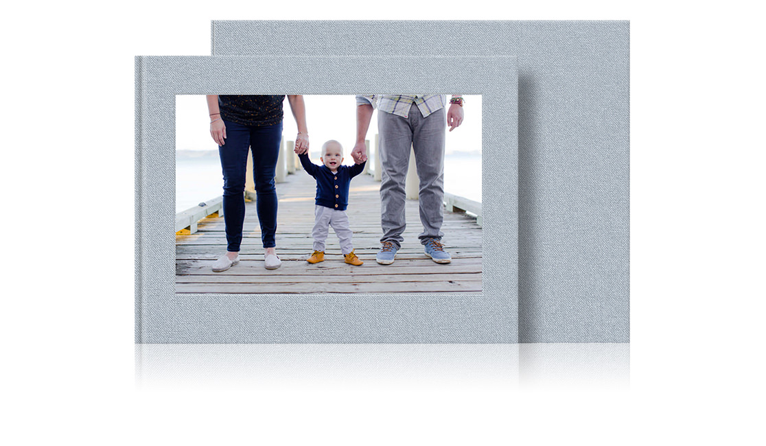 Two photo books with cover image of young child holding hands with parents.