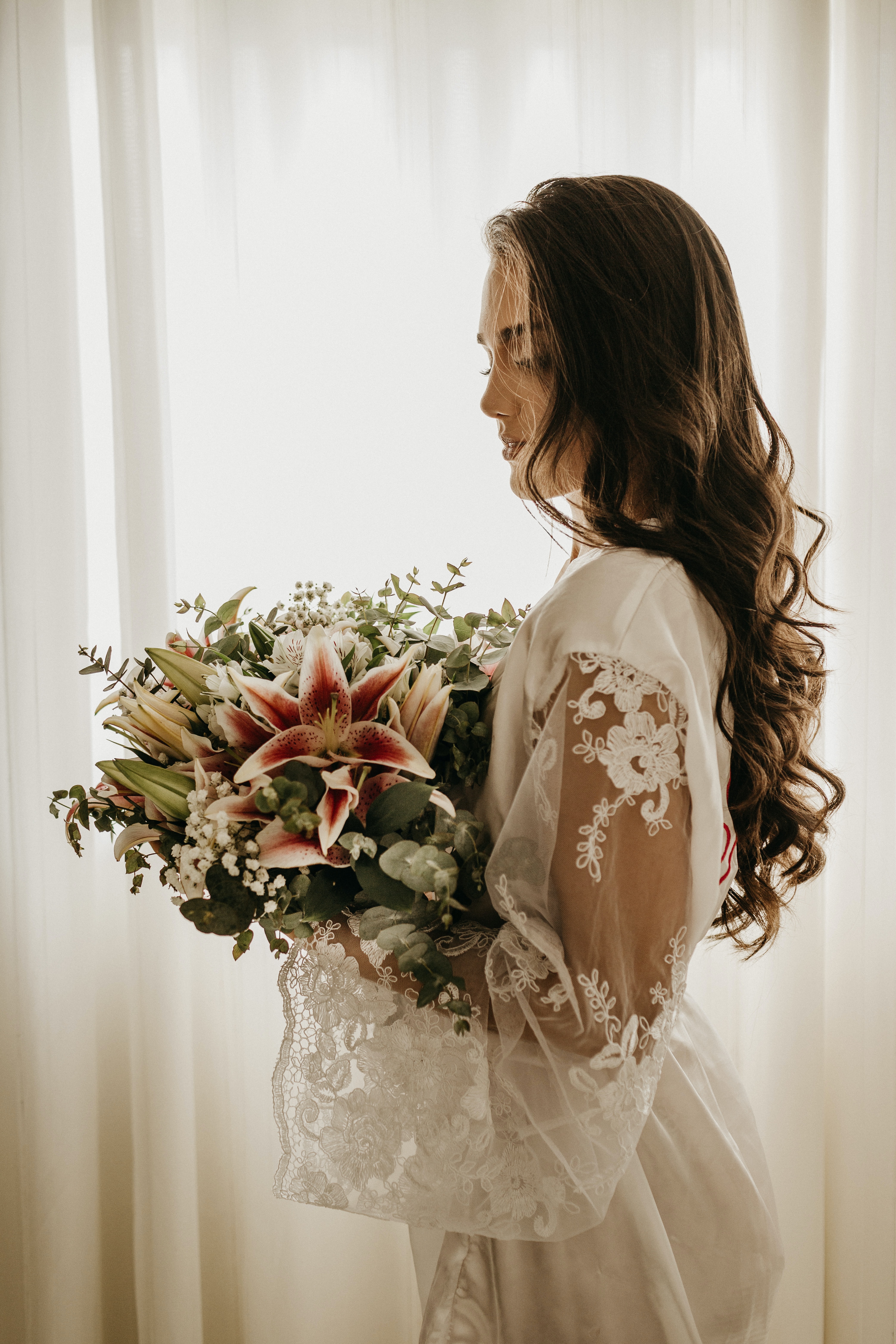 Braut in weißem Kleid hält kunstvollen Blumenstrauß in der Hand.