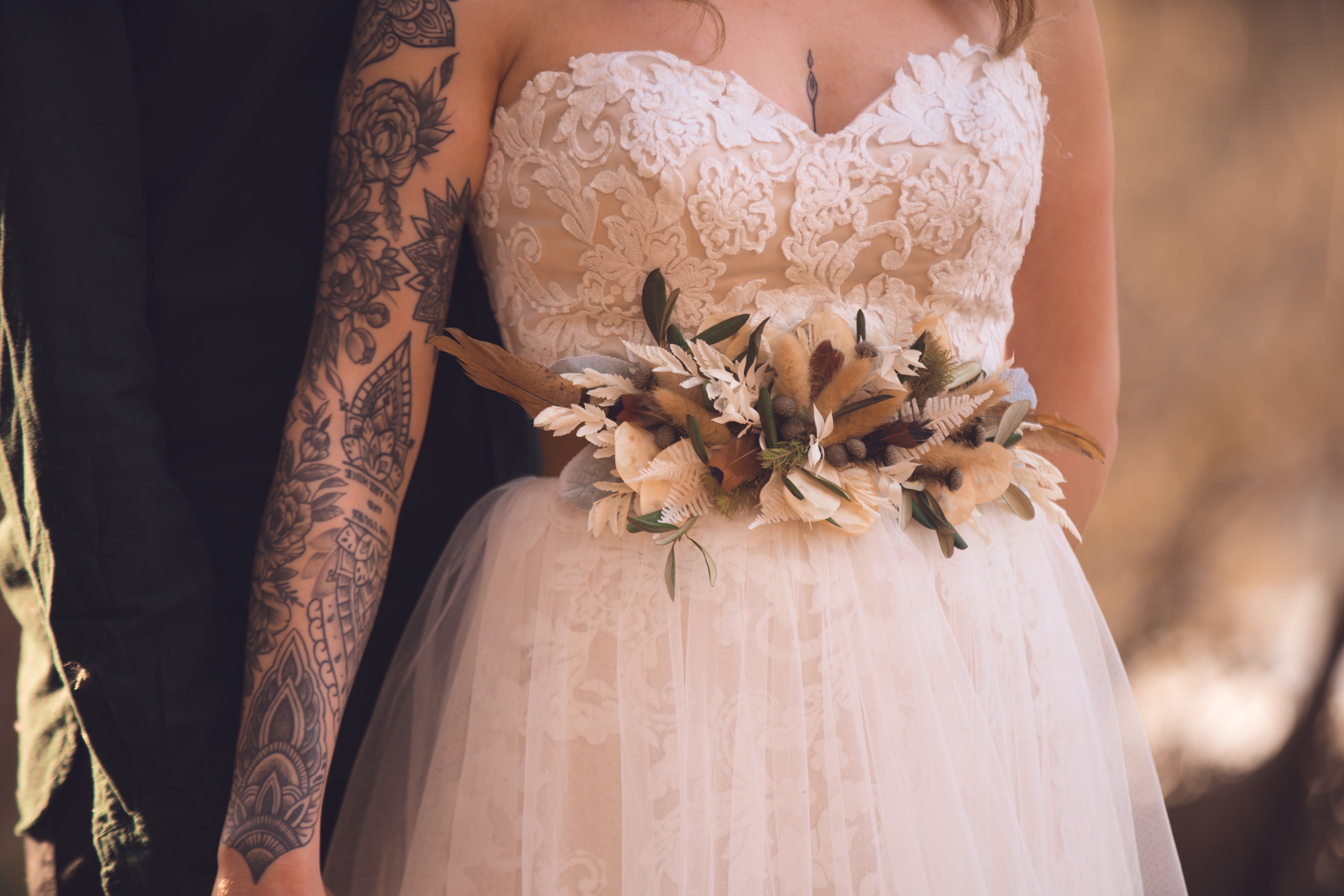 Braut mit kunstvollem Brautstrauß und Tattoo.