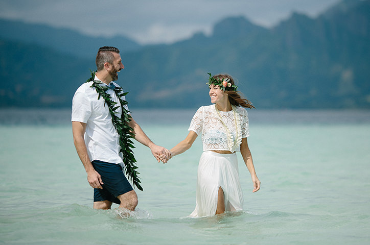 Un couple se tient dans l'eau le jour de leur mariage.