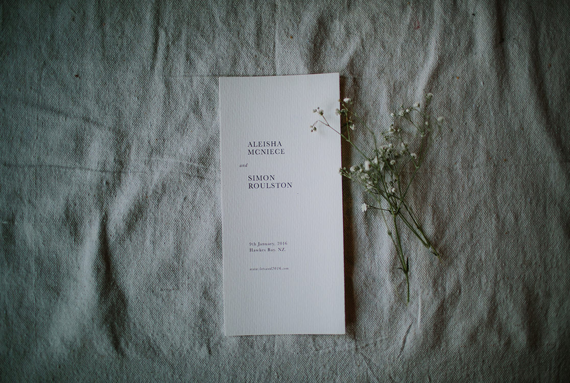 Invitation au mariage à côté d'une branche sur un lit.