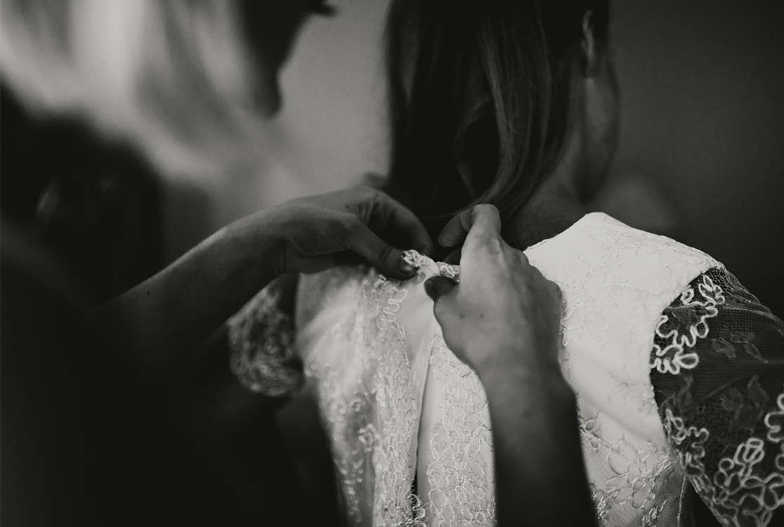 Braut bekommt Hilfe mit ihrem Hochzeitskleid.