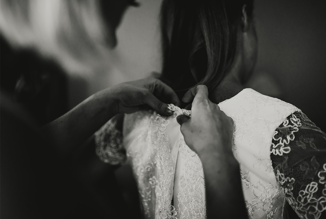 La mariée reçoit de l'aide pour sa robe de mariée.