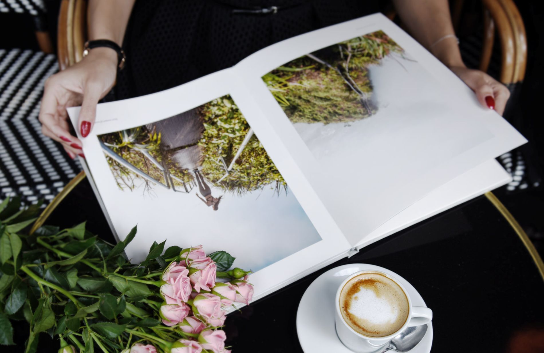 Aufgeschlagenes Fotobuch auf einem Tisch neben einer Tassee Kaffee.