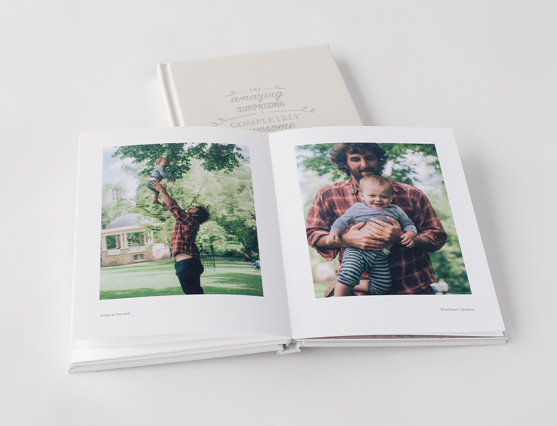 Open premium photo book showing images of man and baby