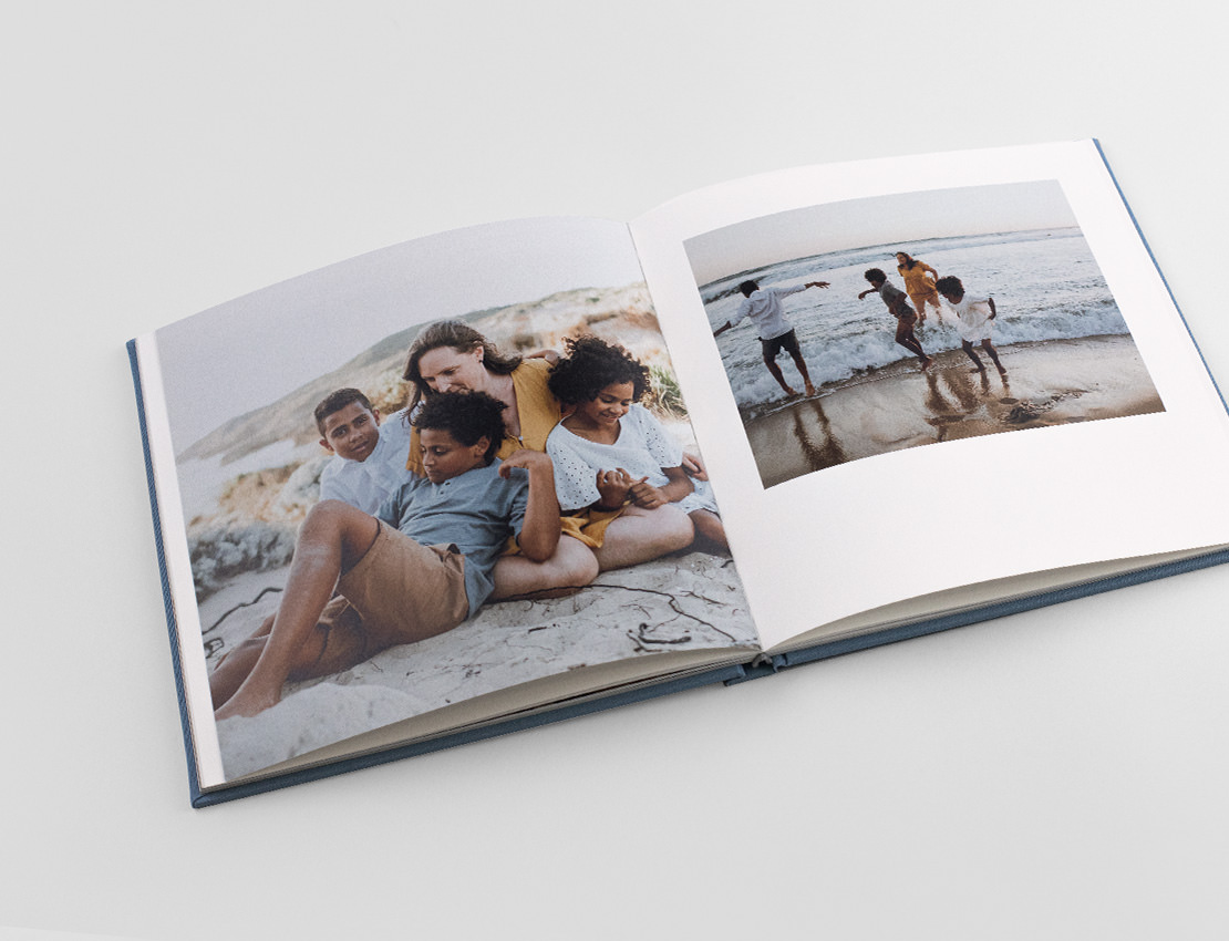 Aufgeschlagenes Premium-Fotobuch mit Bildern der Familie am Strand.