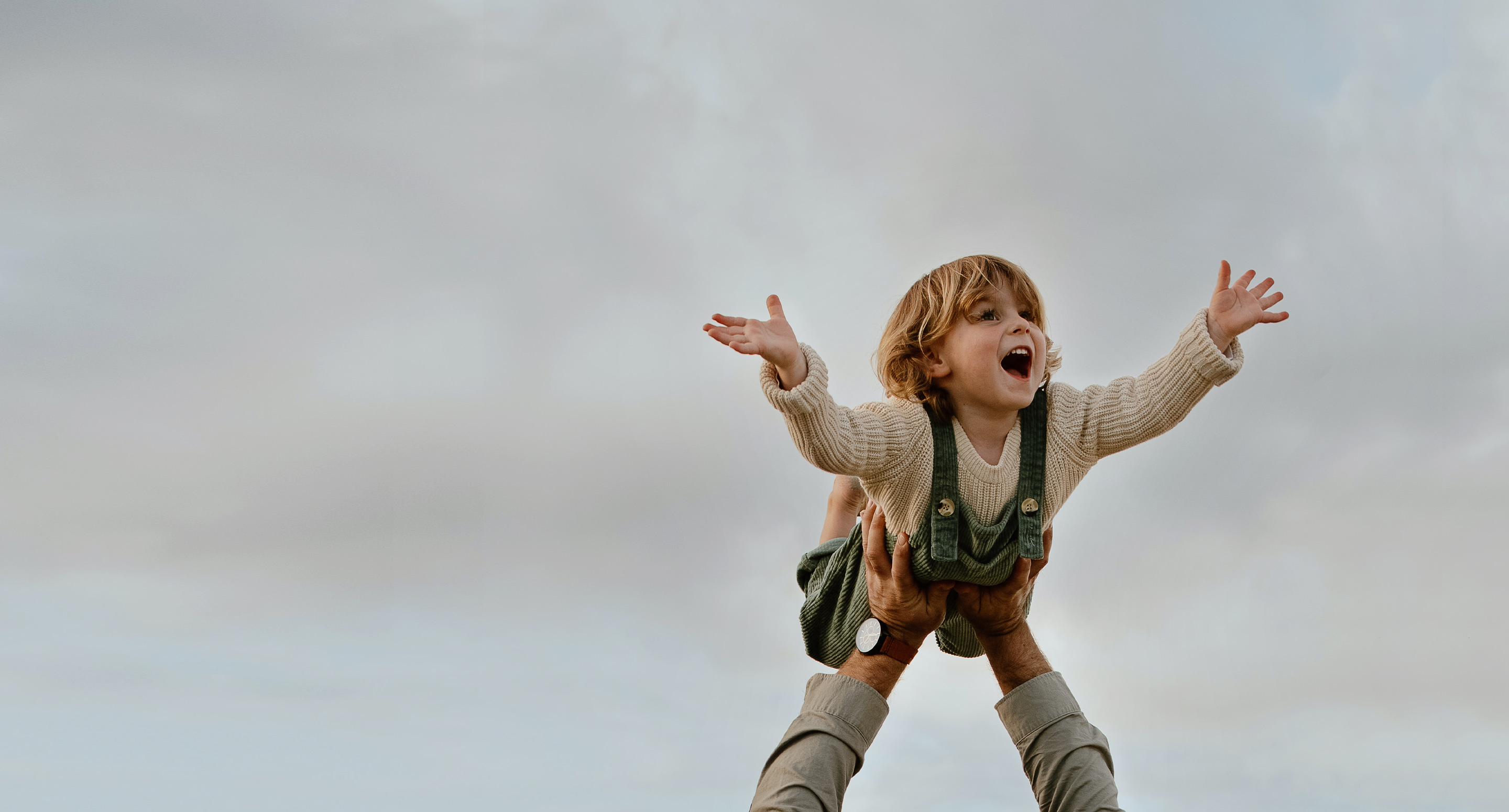 Child in arms against cloudy sky