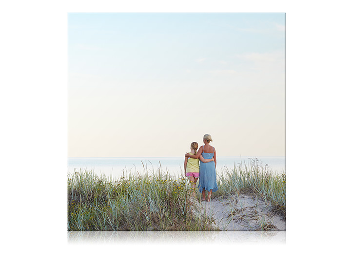 Impression sur toile carrée d'une mère et de sa fille se tenant par les bras à la plage.
