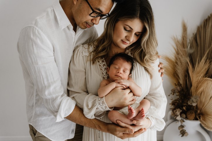 Des parents heureux tenant leur bébé dans leurs bras.