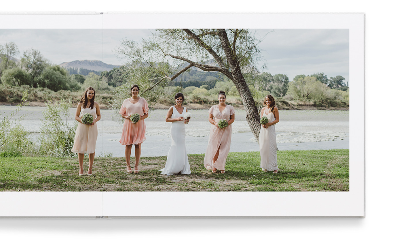 Álbum aberto com foto de noiva com quatro amigos segurando buquês de noiva.