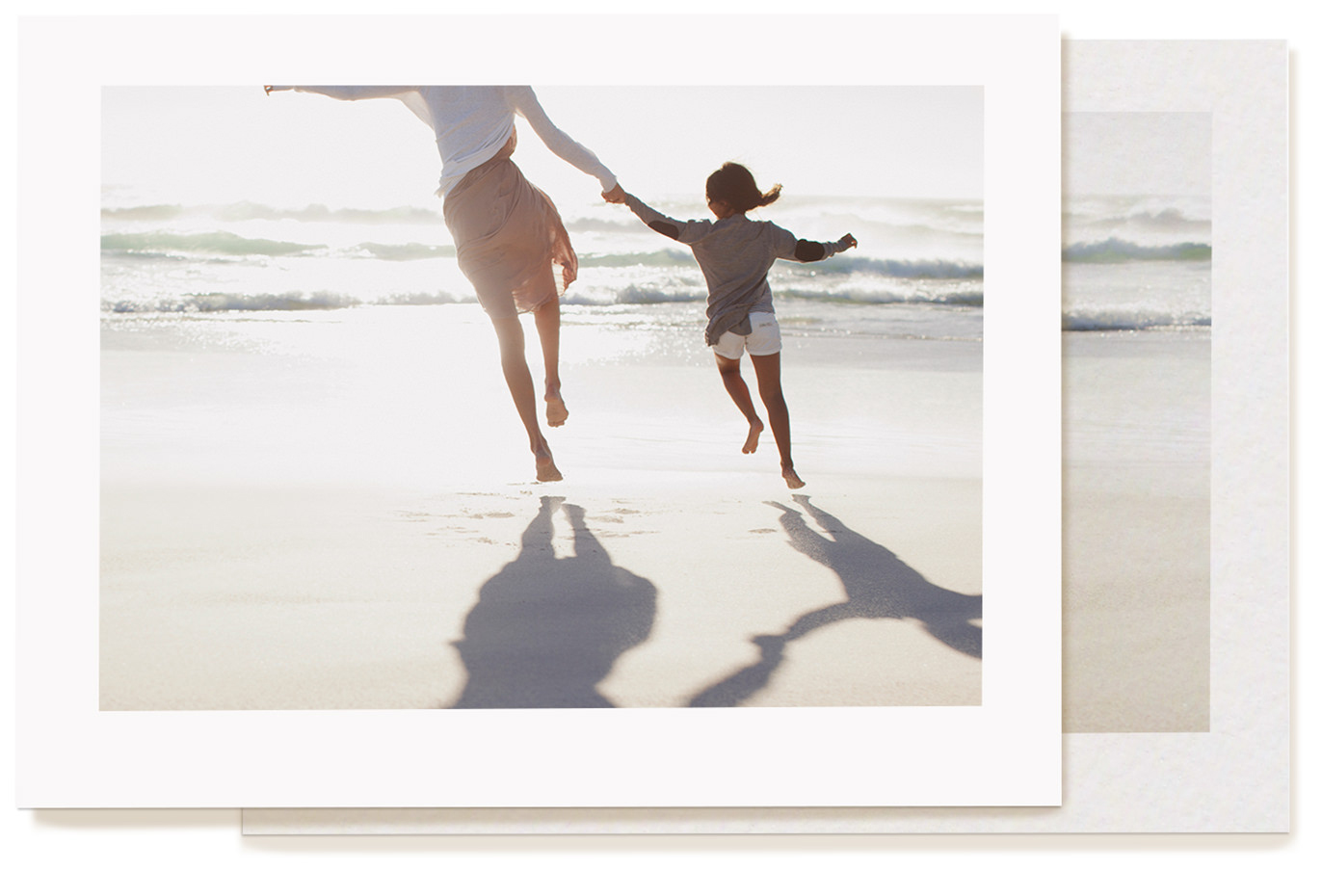 Imagem de uma foto impressa em papel MILK "Photo Lustre". Na foto, mãe e filha estão caminhando de mãos dadas junto ao mar.