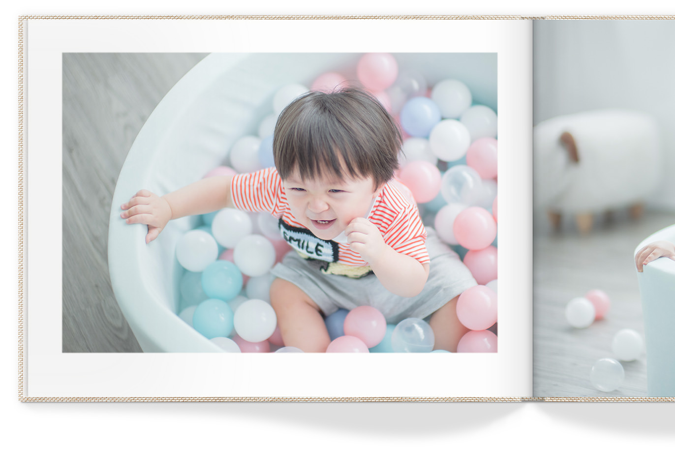Página de livro aberta com menino risonho em uma piscina de bola colorida.