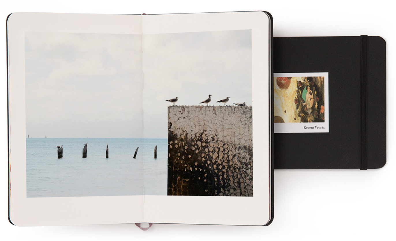 Um livro Moleskine aberto com gaivotas na página aberta e um livro fechado com arte na capa.
