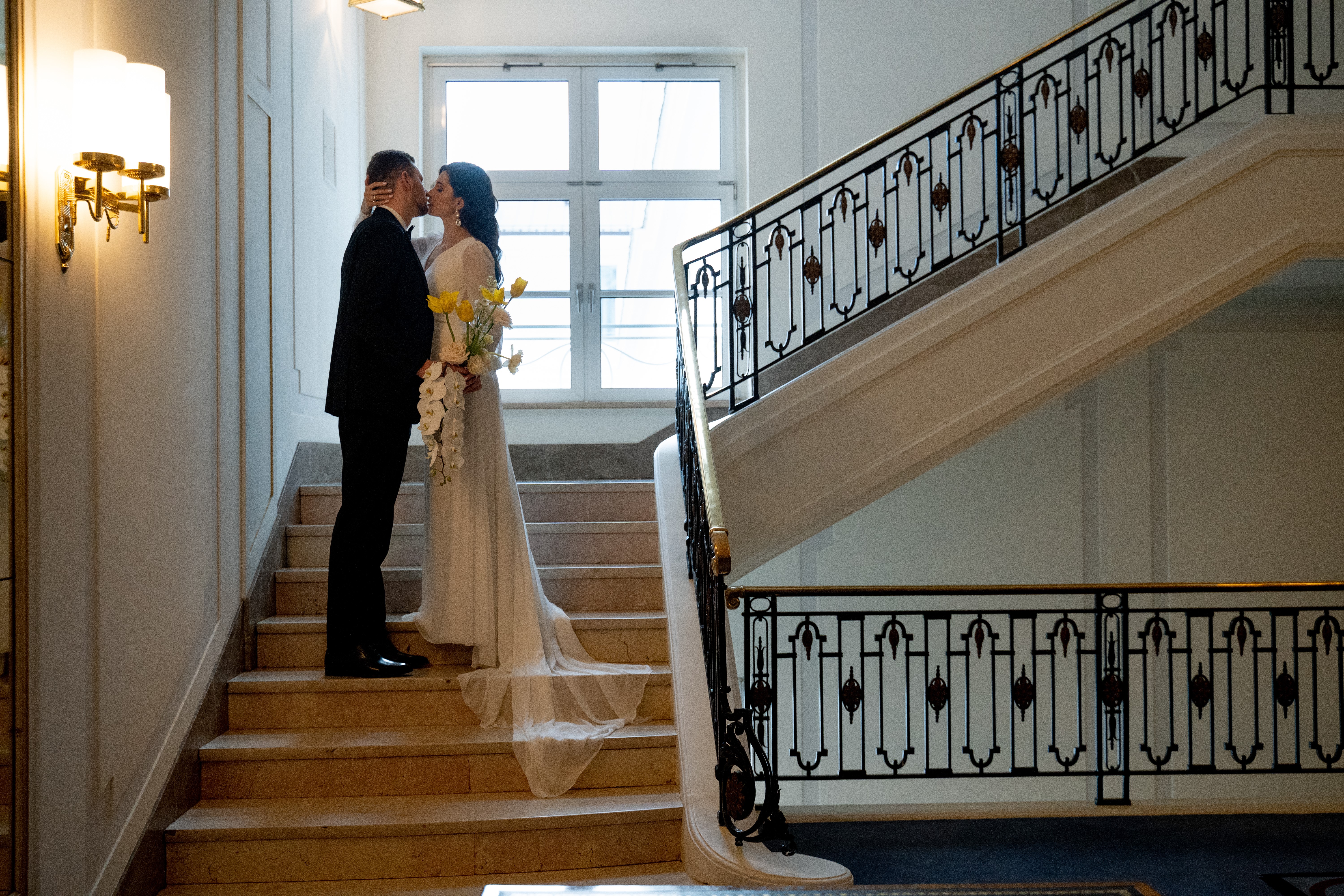 Brautpaar küsst sich im Treppenhaus.