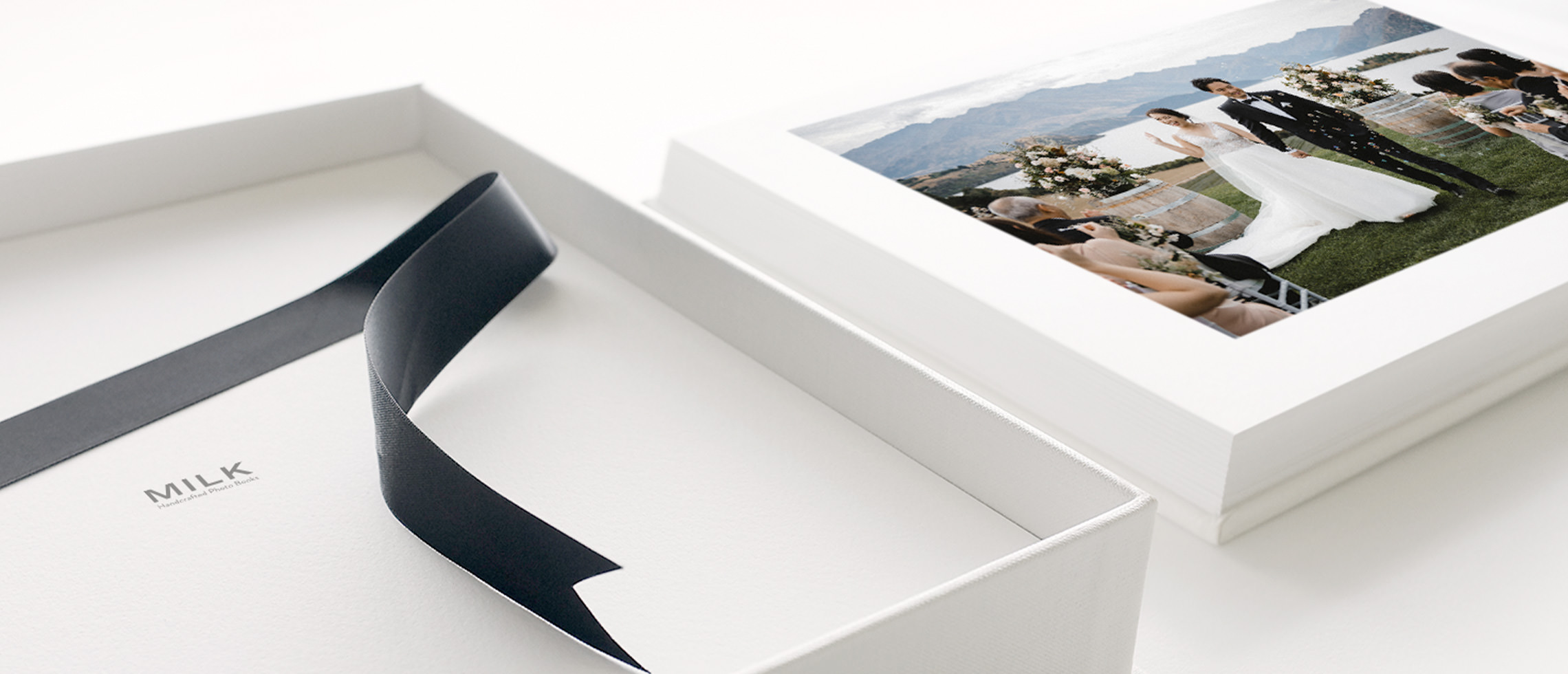 Photo album presentation box with fine silk lift-out ribbon and archival quality photo wedding album with a cover photo of newlyweds by the mountains and lake.