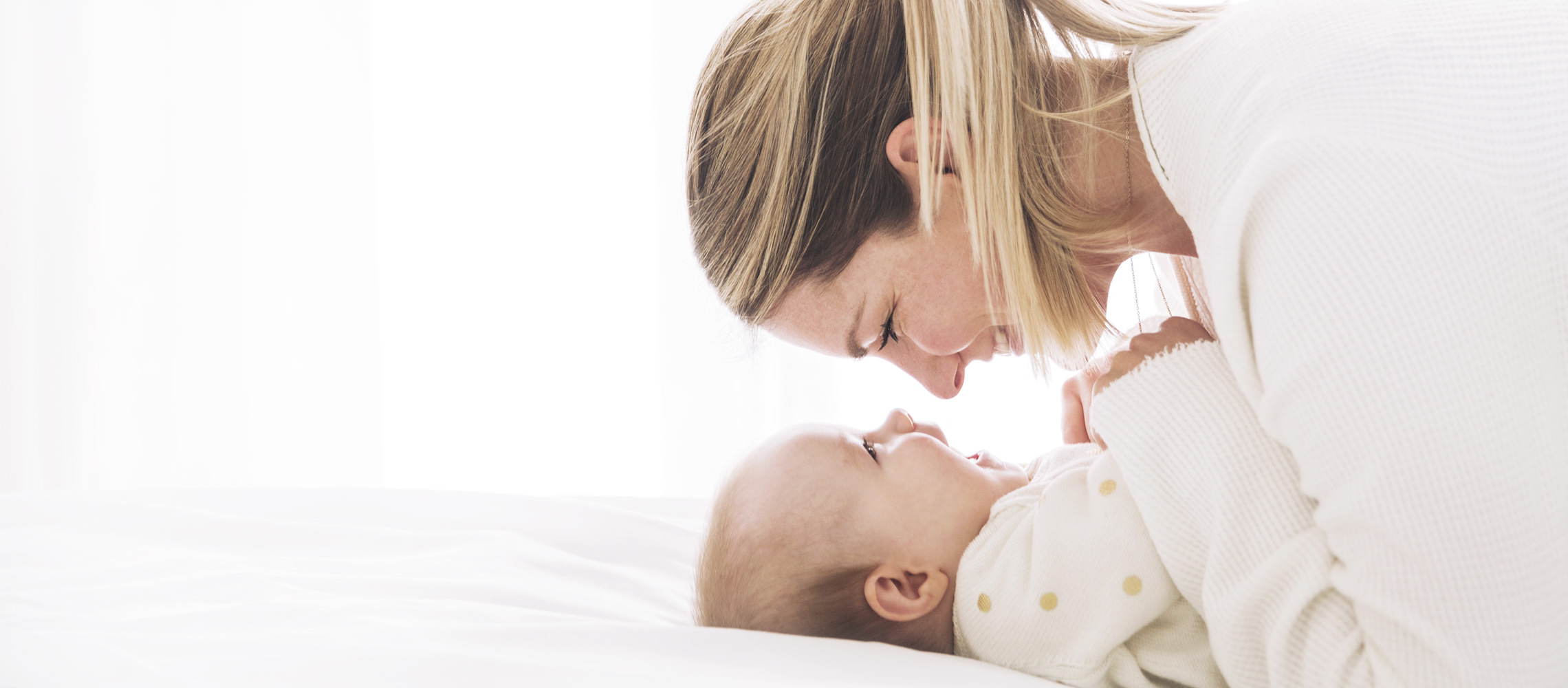 Mother and baby smiling looking into each other's eyes.