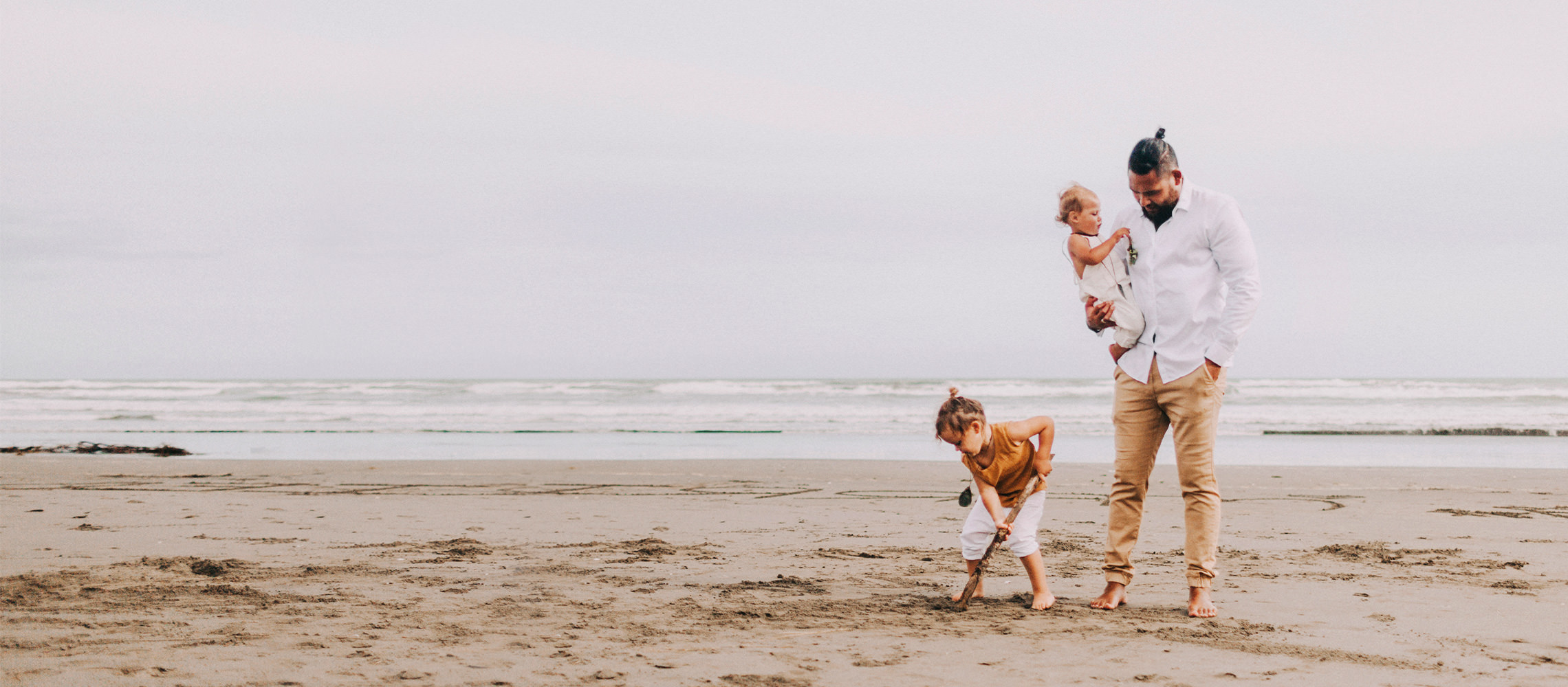 Padre con sus hijos jugando en la arena.