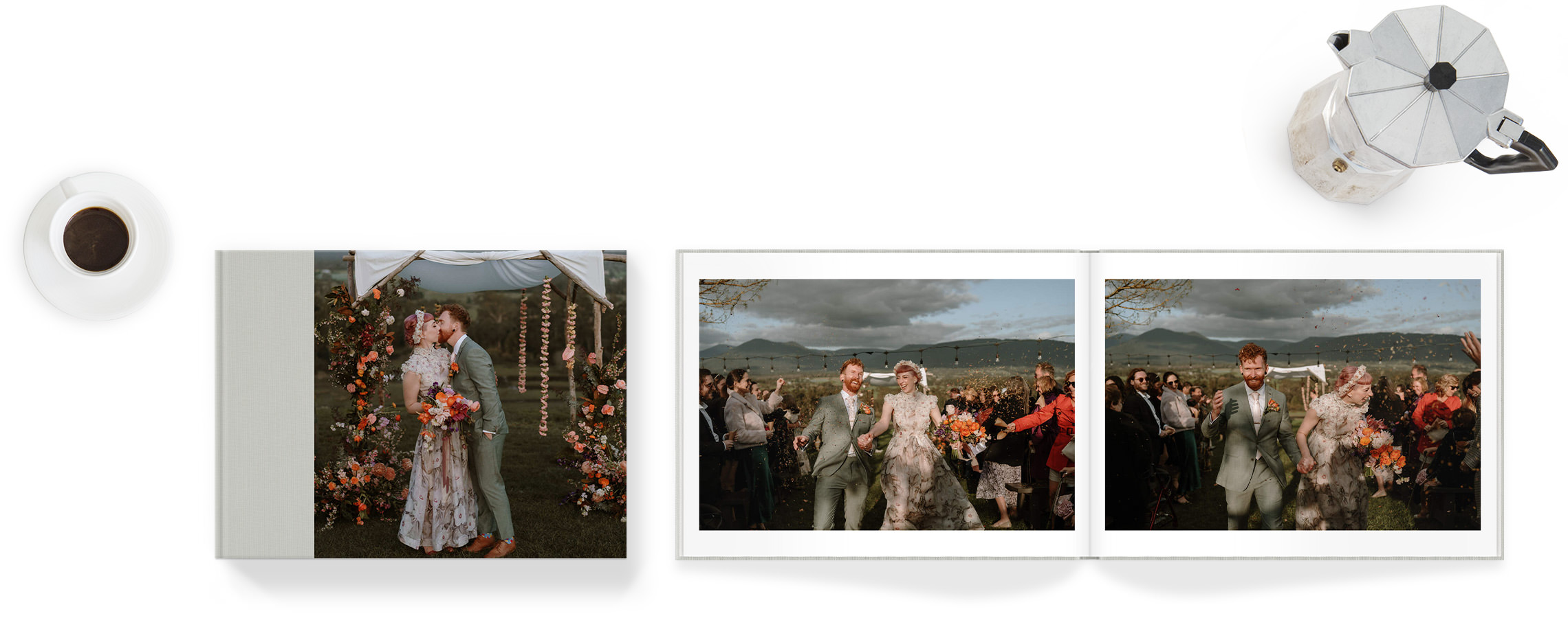 Open landscape photo book with wedding couple inside - book in on white background with cup of coffee and moka pot on either side