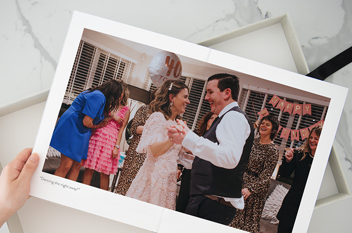 Open photo book being held pages show couple dancing at birthday party wearing pink colors