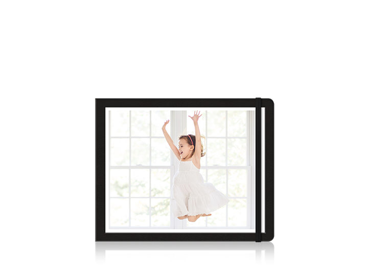 Moleskine-Fotobuch mit einem springendem und lachendem Mädchen auf dem Cover.