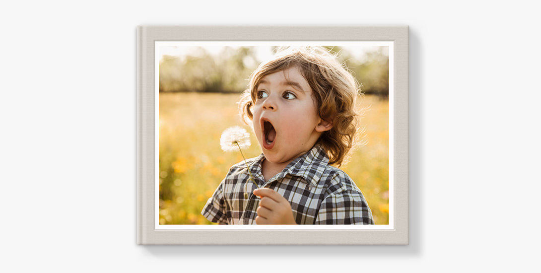 Photo book with cover image of boy blowing a dandelion.